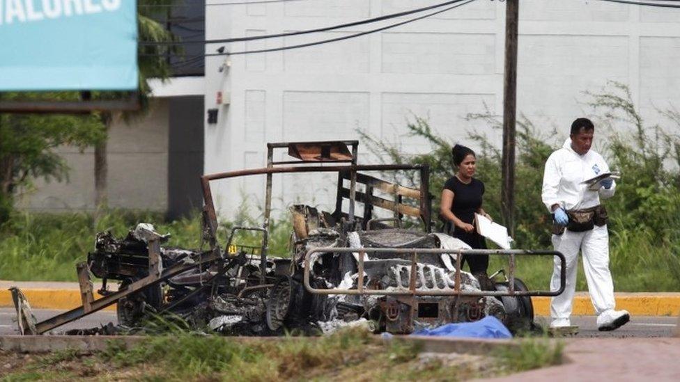 Forensic experts stand next to a burned vehicles after an ambush perpetrated by alleged members of an organized crime syndicate in Culiacan, Sinaloa, Mexico (30 September 2016)