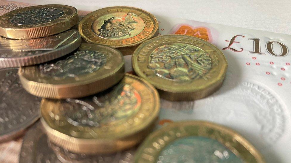 A pile of £1 coins on top of a £10 bank note