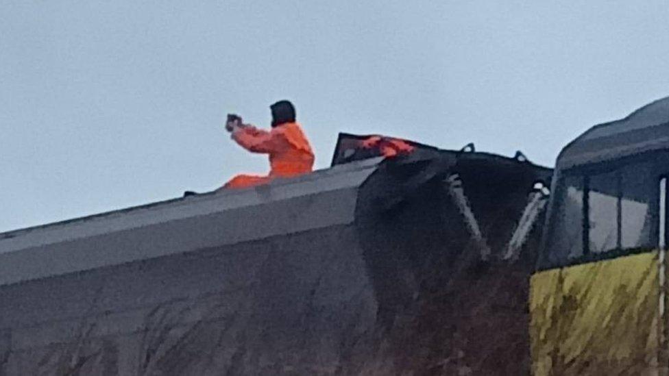 Activist wearing orange suit sitting on top of a train