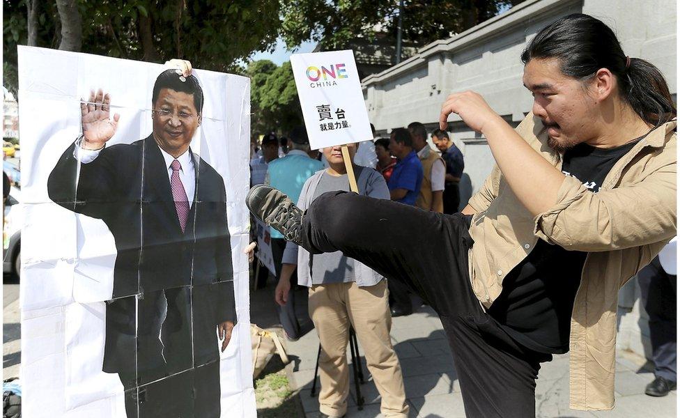 An activist kicks a portrait of Chinese President Xi Jinping during a protest against the upcoming meeting between Taiwan's President Ma Ying-jeou and Chinese President Xi Jinping, in front of the Presidential Office in Taipei, Taiwan, 5 November 2015.