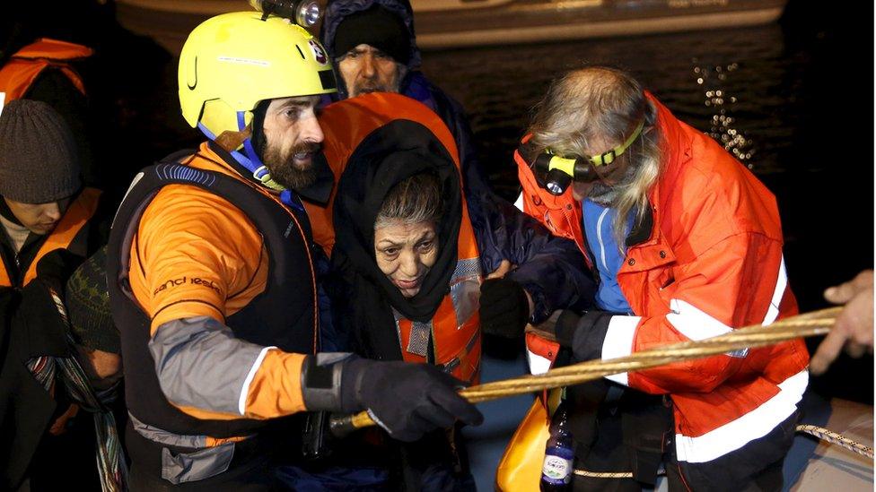 Volunteers help an Afghan refugee off a raft on Chios (28 Jan)