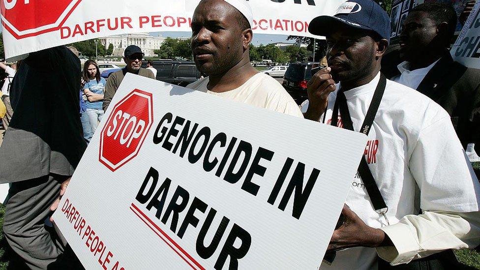 Man holding a sign saying "Stop genocide in Darfur"