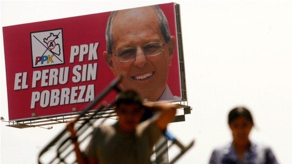 People walk next to a billboard calling for a country without poverty as part of the presidential campaign of candidate Pedro Pablo Kuczynski, leader of Alianza por el Gran Cambio, in Lima on April 7, 2011