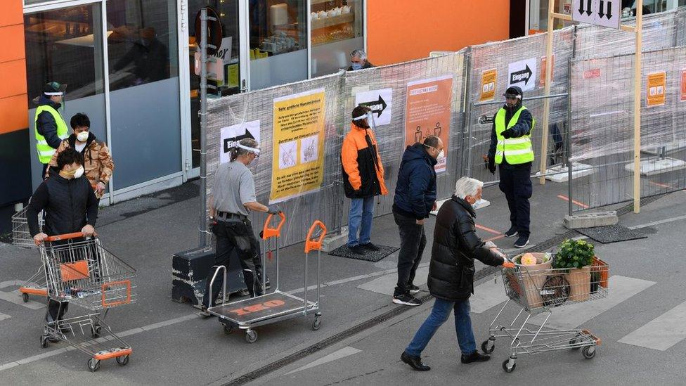 Customers wearing face masks push shopping carts in front of a DIY store in Vienna on 14 April