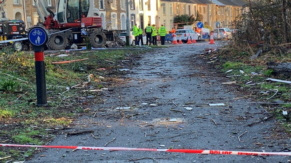 Police cordon and digger cleaning up rubble at Morrison explosion scene