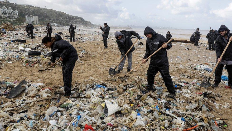 Workers clean the beach of the coastal town of Zouk Mosbeh, north of Beirut, on January 23, 2018