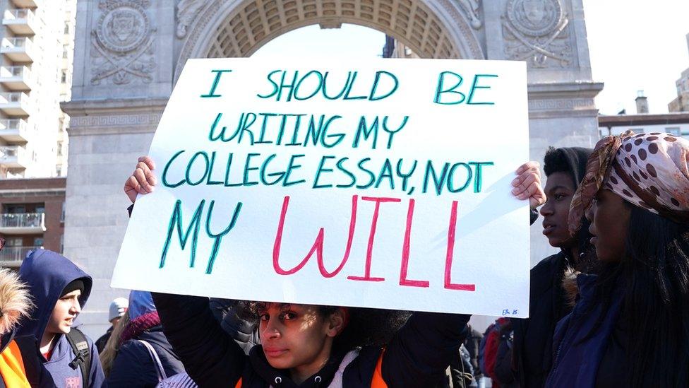 "I should be writing my college essay, not my will" reads a student's sign in New York