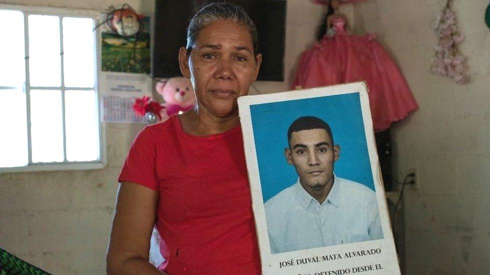 Marcela Alvarado holds a placard with a photo of her jailed son