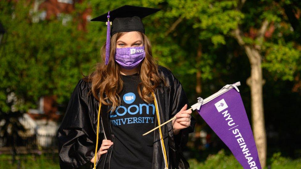 A student wears a protective face mask, graduation cap and graduation gown in Washington Square Park during the coronavirus pandemic on May 15, 2020