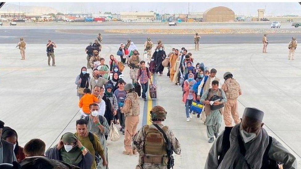 Afghans and Spanish citizens residing in Afghanistan board a military plane as part of their evacuation