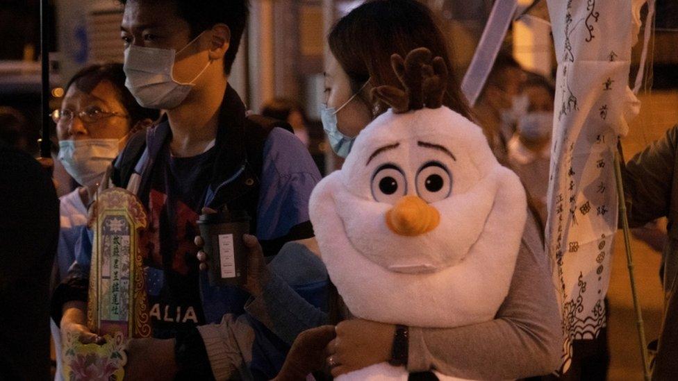 A woman holding a stuffed Olaf toy