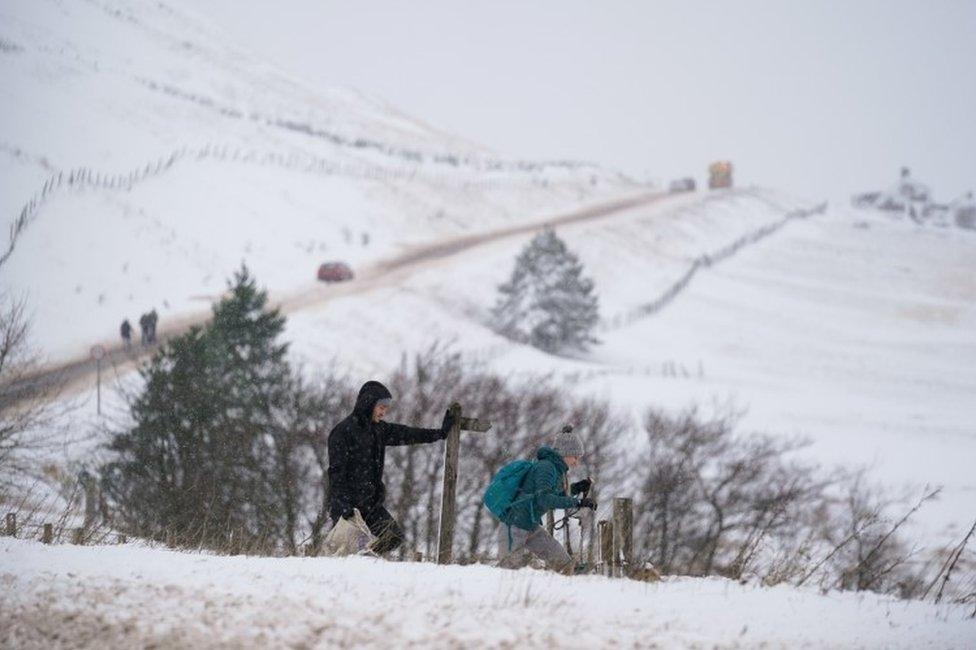 Walkers cross field covered in snow by the A53 close to Buxton in Derbyshire, amid freezing conditions in the aftermath of Storm Arwen