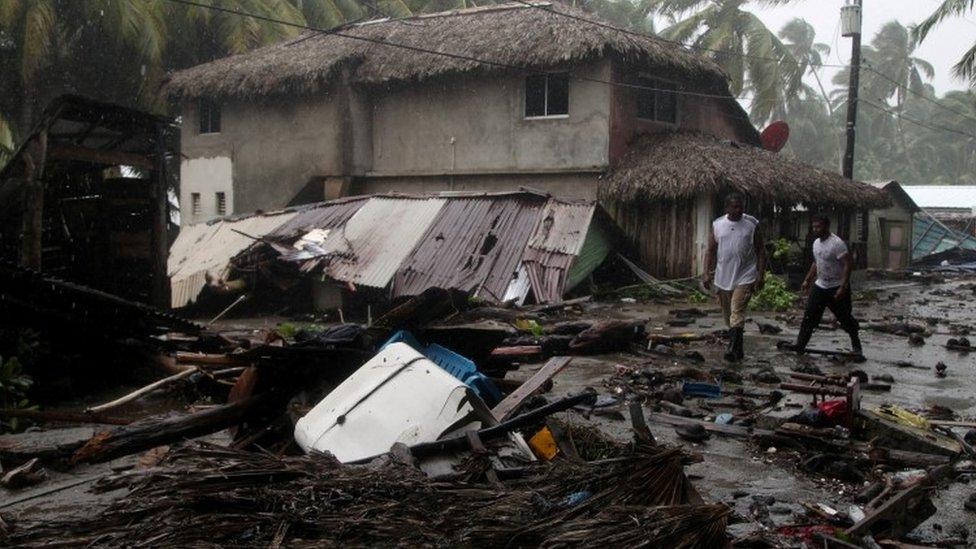 People walk past debris as Hurricane Irma moves off from the northern coast of the Dominican Republic, in Nagua