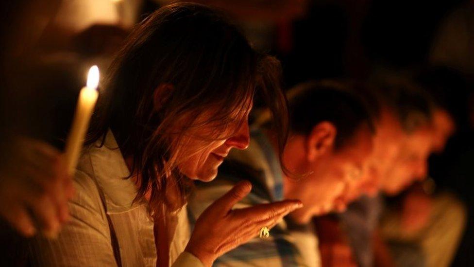 A woman reacts as people place candles outside the Instituto Politecnico