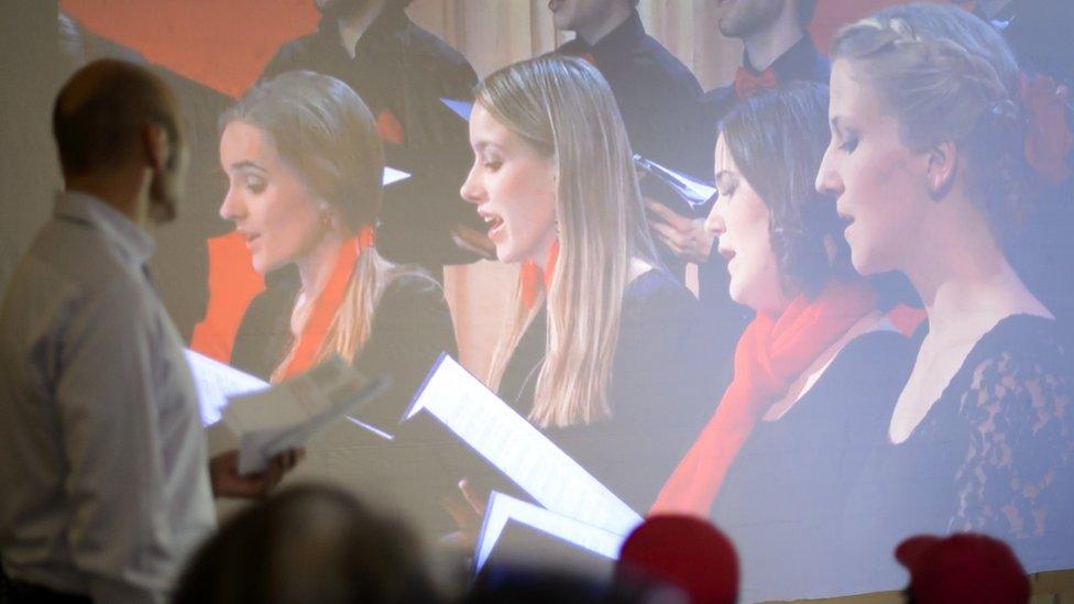 A man watches a choir perform one of the final songs in the competition for a Swiss anthem