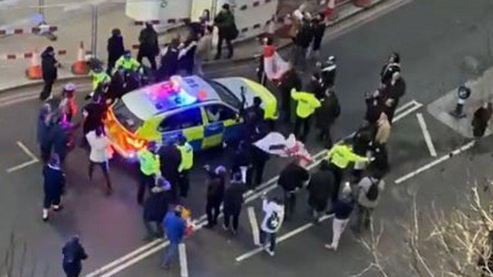 A police car surrounded by protesters in Westminster