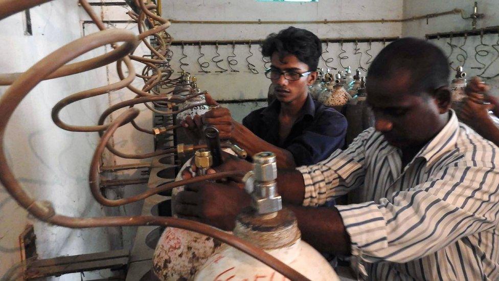 Indian workers examine oxygen cylinders at the Baba Raghav Das Hospital in Gorakhpur, in the northern Indian state of Uttar Pradesh