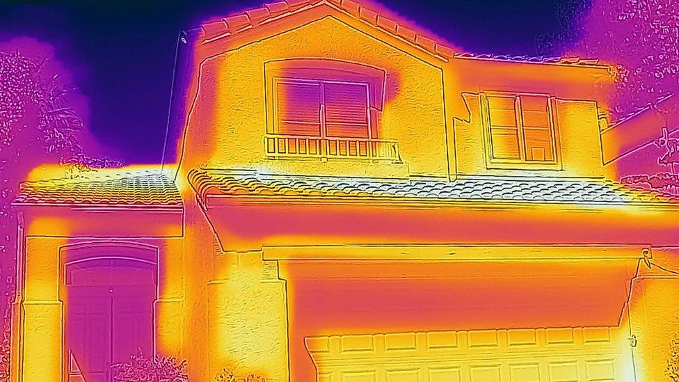 Thermal imaging camera showing heat loss from a house