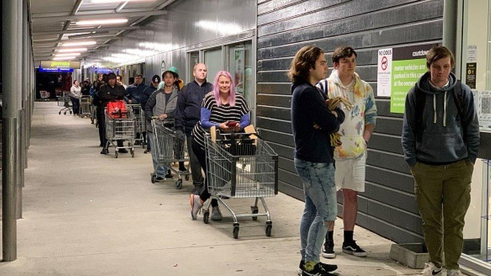 Shoppers wait to enter a supermarket in the suburb of Johnsonville in Wellington