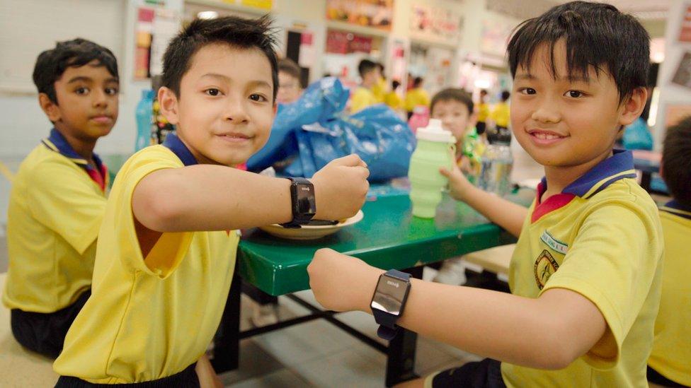 Children at Admiralty High School in Singapore show off their new payment wristbands