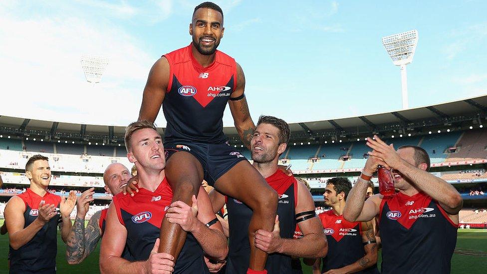 Héritier Lumumba carried on the shoulders of his Melbourne Football Club teammates in a post-match celebration