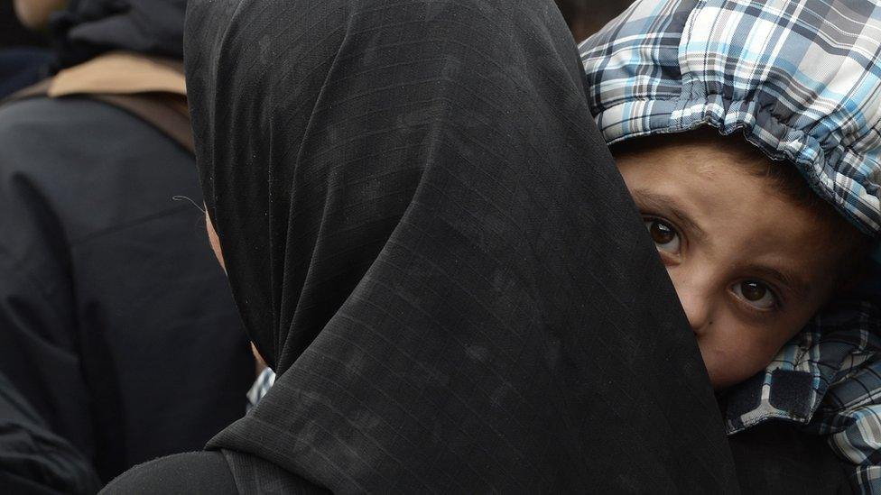 Refugees walk to the bus after a first police check in a tent near the central train station in Passau, southern Germany, on 8 October 2015