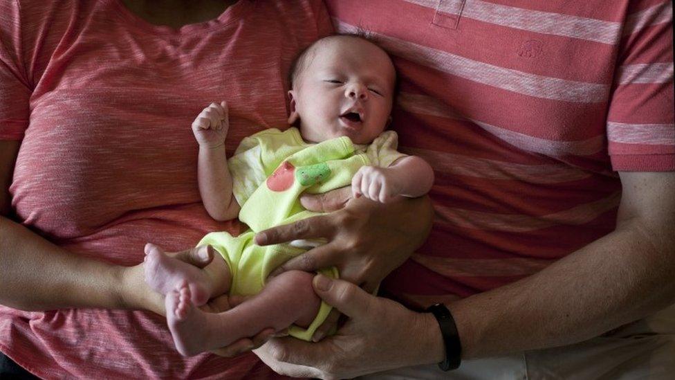 In this Nov. 5, 2015 file photo, a couple from Britain hold their baby, born on Oct. 17 by a surrogate, in Anand, India