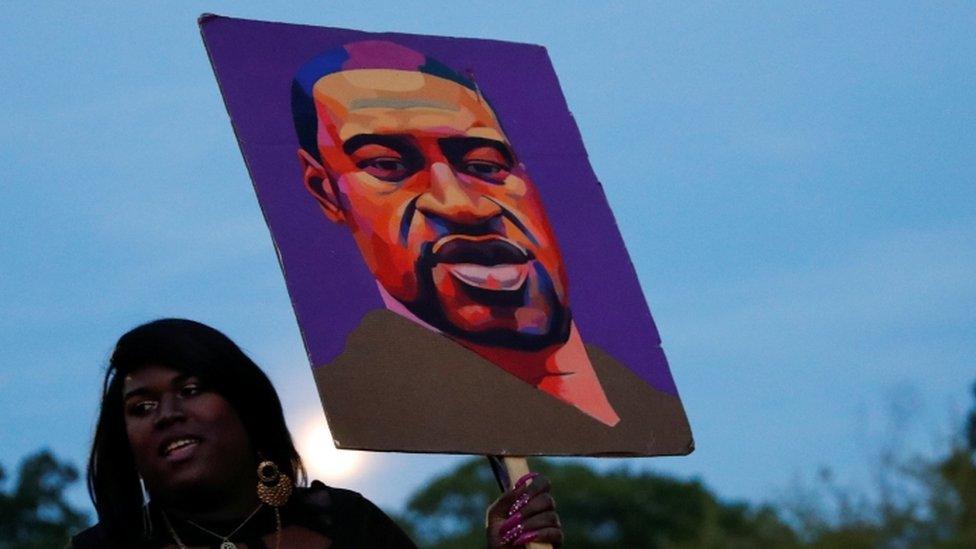 Woman holds a poster of George Floyd at a rally in Brooklyn, NY 25 May 2021