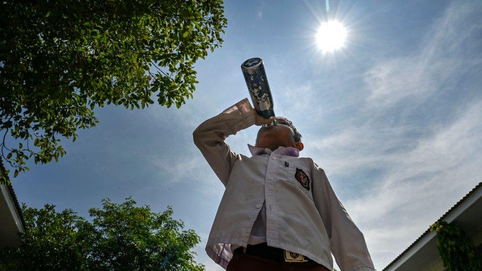 Boy drinking water underneath the sunshine