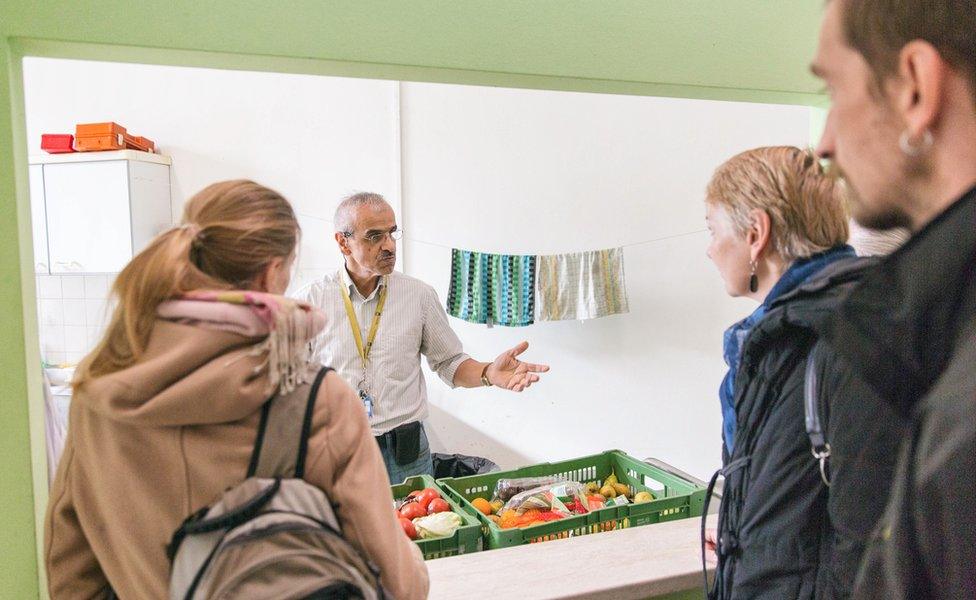 A handout photo of a tour guide speaking to people at the shelter