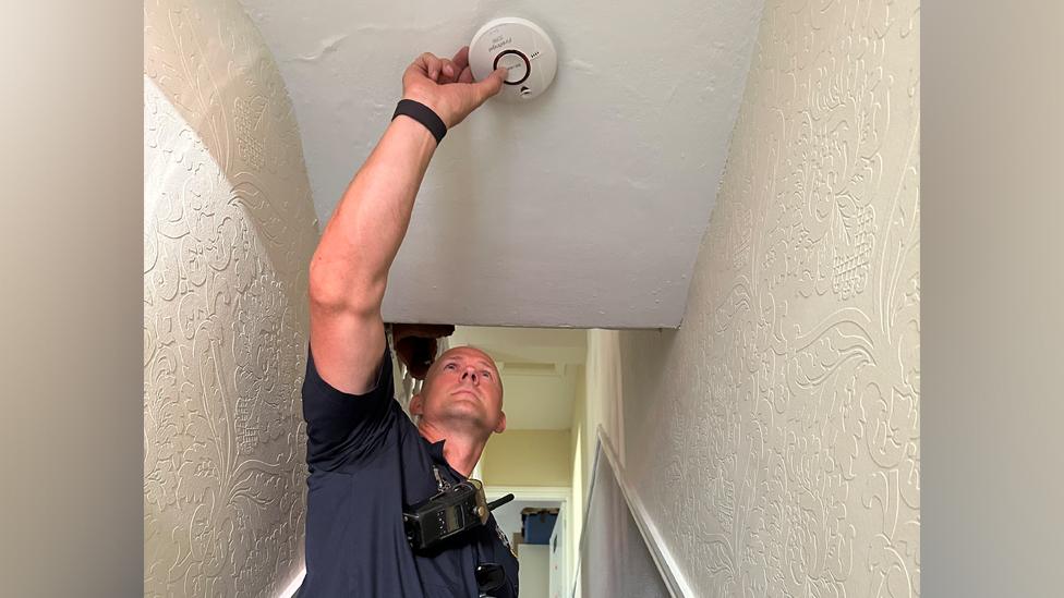 Firefighter testing smoke alarm