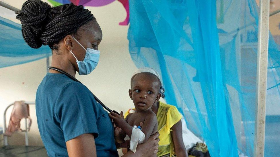 Dr Sila holds a small baby in her arms in a hospital