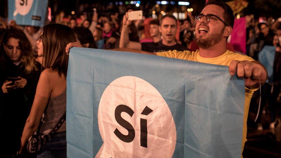 Crowds listen to Catalan President Carles Puigdemont speak via a televised press conference at the Placa de Catalunya on October 1, 2017 in Barcelona