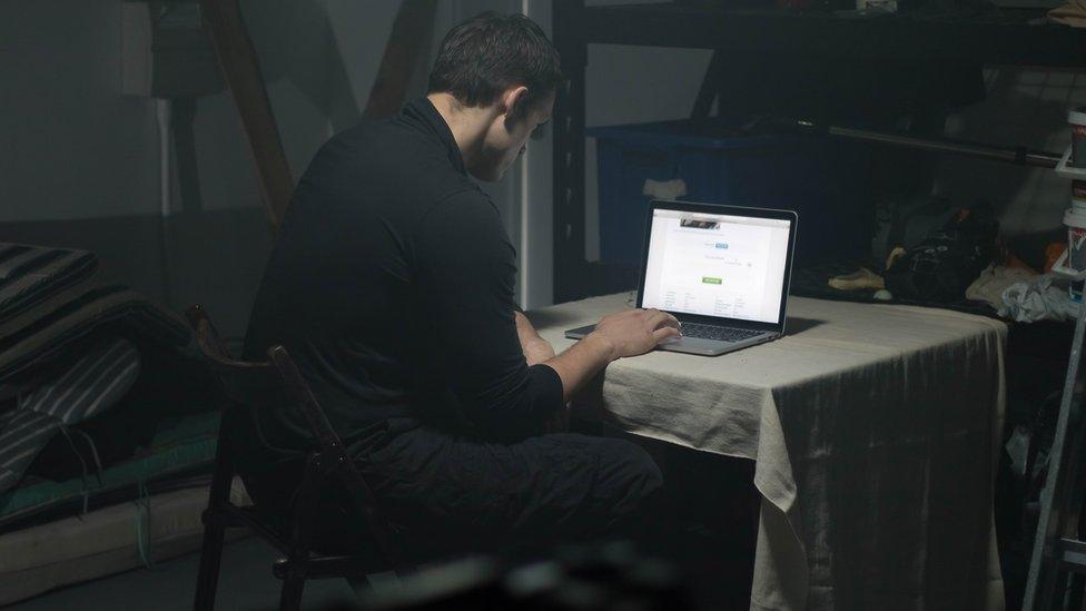 Man using laptop in darkened room