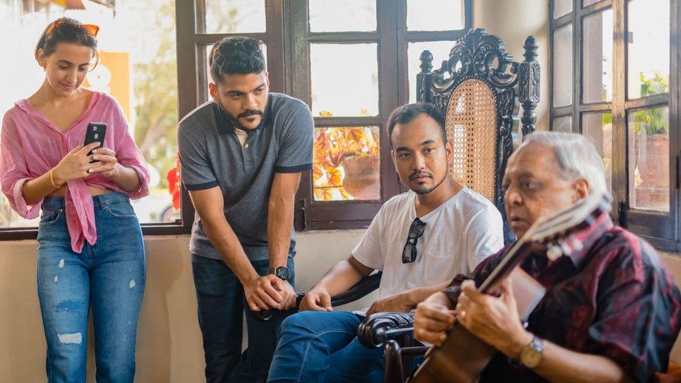 Tourists listen to a musical performance at a house in Goa's Panjim