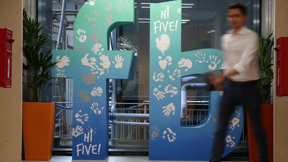 Man walks past Facebook sign