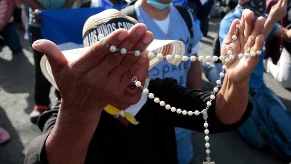 People pray in front of police that block the entrance of Divine Mercy Catholic Church in Managua, Nicaragua July 14, 2018