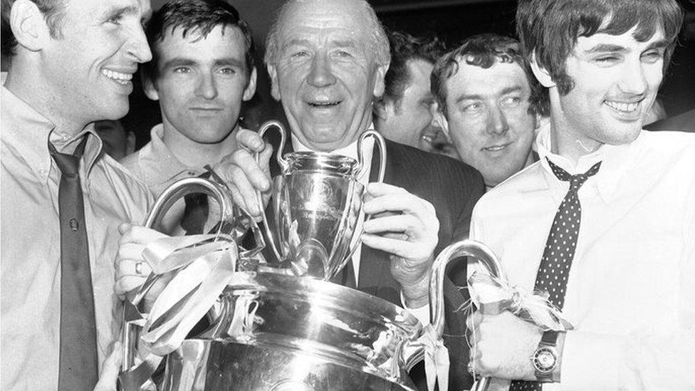 Pat Crerand, left, and George Best, right, of Manchester United hold the European Cup with their manager Matt Busby at Euston Station, London, prior to the team's departure for Manchester 1968 file photo.