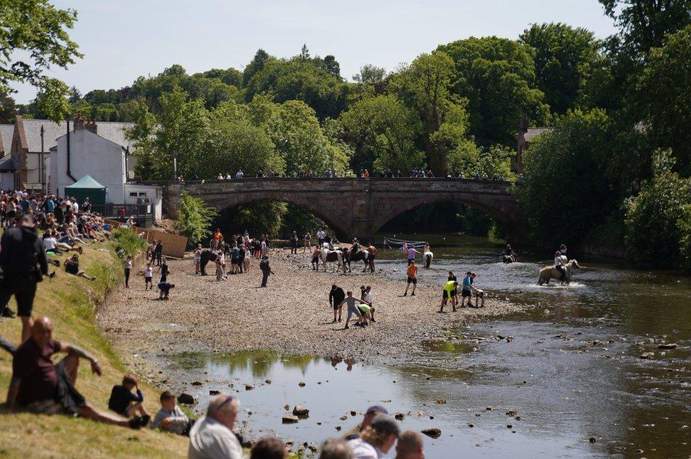 People ride their horses through the river during the Appleby Horse Fair