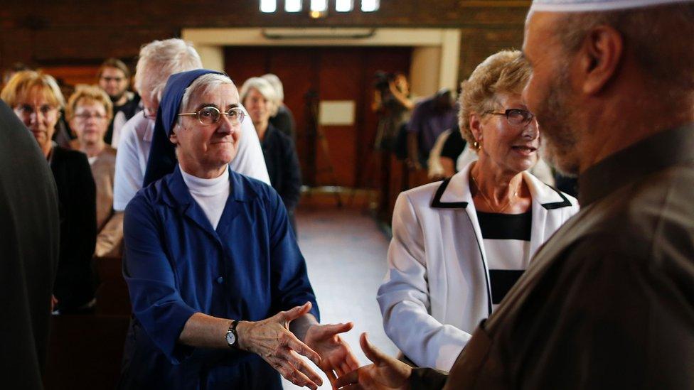 Nun shakes hands with a Muslim in Sainte-Therese church during a mass in tribute to priest Jacques Hamel on July 30, 2016 in Saint-Etienne-du-Rouvray