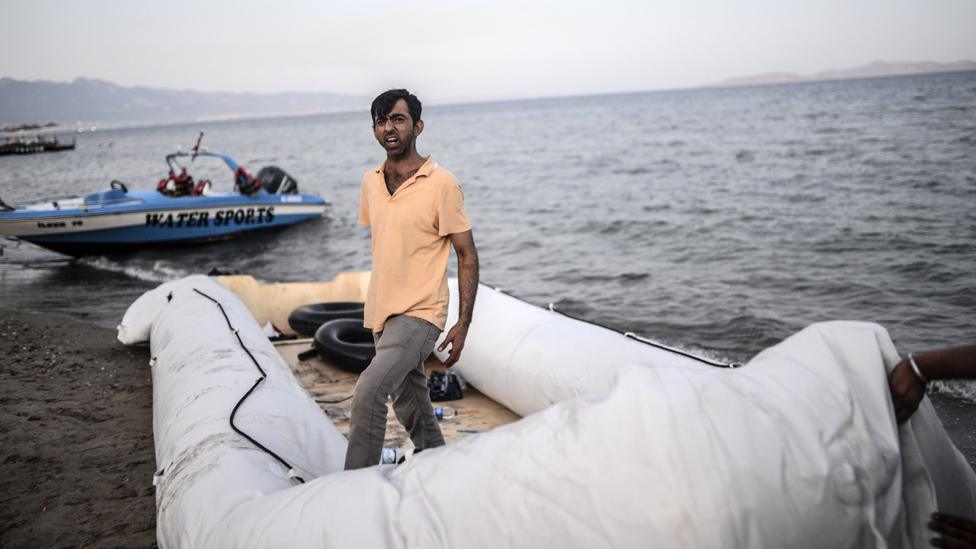 A man stands on a boat abandoned on the shore of Bodrum, southwestern Turkey, early on August 19, 2015.