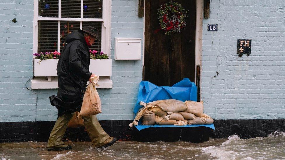 A person places sand bags outside a property in Langstone, Hampshire