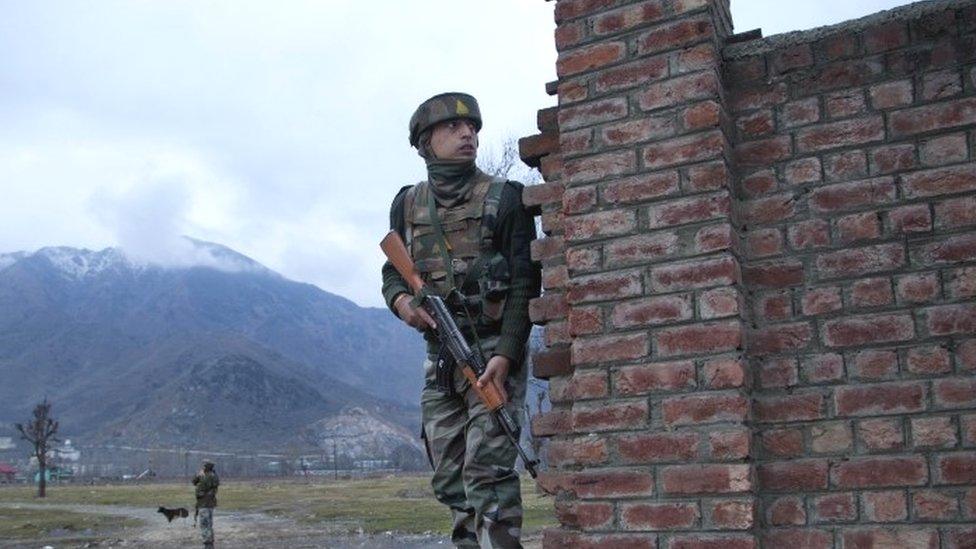 An Indian soldier watches from a distance as he takes position behind a wall near the site of the gun battle on the outskirts of Srinagar (20 February 2016)