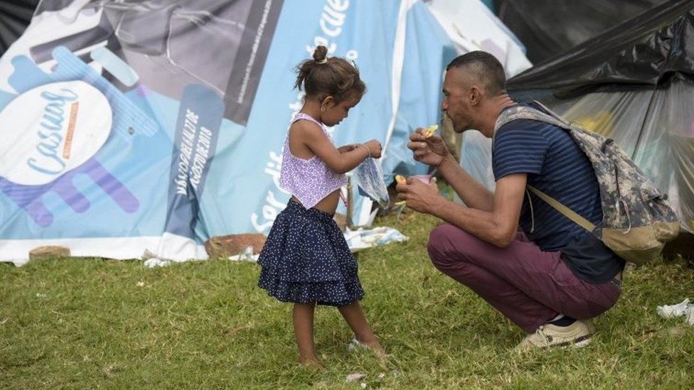 A Venezuelan migrant man and a girl are pictured at an improvised camp near the bus terminal in Bogota on September 11, 201