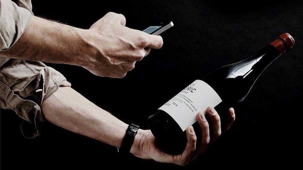 Man scanning wine bottle label with smartphone