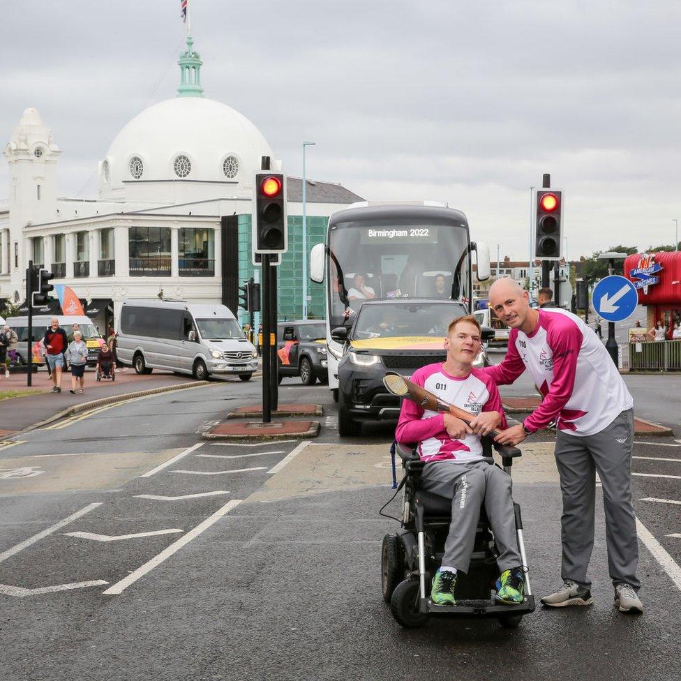 Paralympian Stephen Miller and Paul Harris carry the baton at Whitley Bay with Spanish City in the background