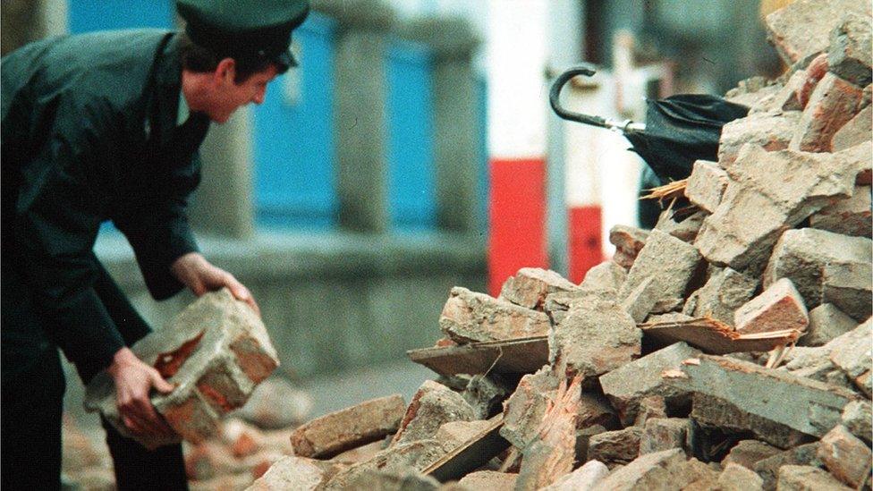 Man in uniform digs through rubble