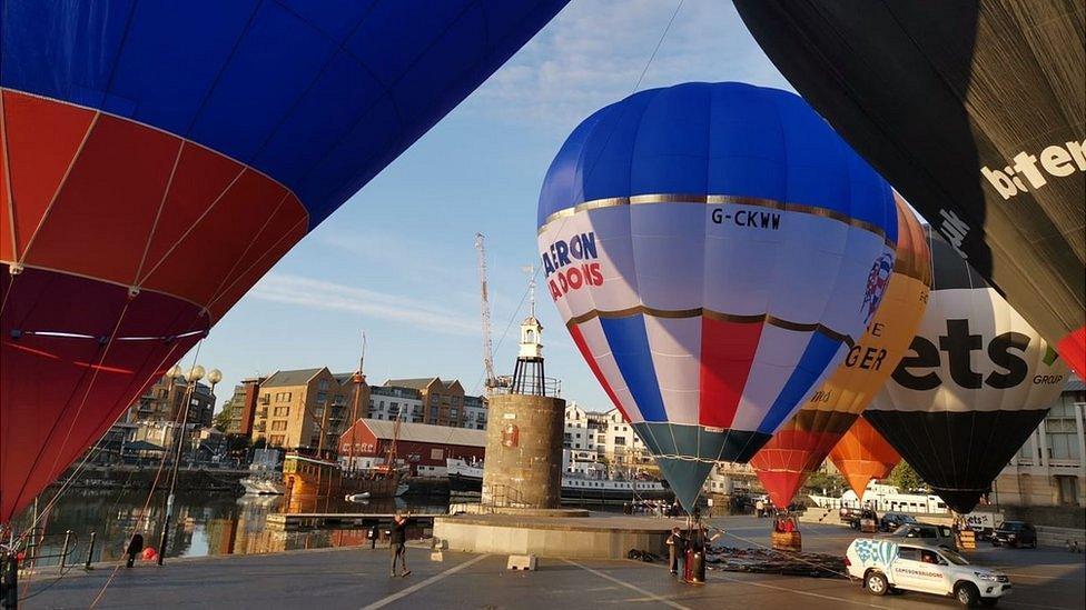 A blue and white hot air balloon being inflated at Bristol's harbourside