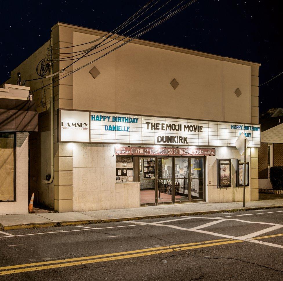 A night view of a cinema with a birthday message on the sign above the door