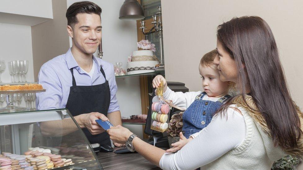 Woman with baby paying in a cake shop